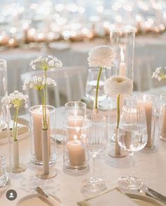 a table topped with lots of vases filled with flowers next to candles and plates