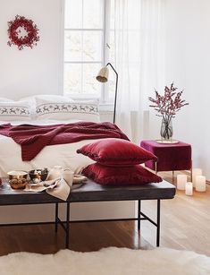 a bedroom with white walls and wooden flooring is decorated in red, white and black