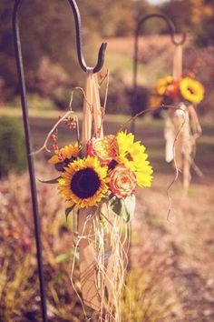 two sunflowers are in a glass jar on a pole with an oar