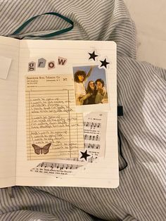 an open notebook with photos and writing on it sitting on top of a bed covered in sheets