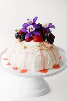 a white cake topped with berries and flowers