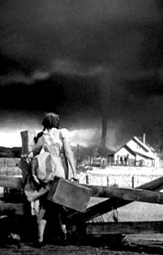 black and white photograph of people carrying suitcases in front of an overcast sky