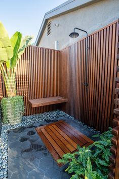 a wooden bench sitting in the middle of a garden next to a shower and plants