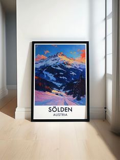 a framed poster is sitting on the floor in front of a window with an image of a snowy mountain