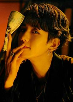 a young man talking on a cell phone while holding money in his hand