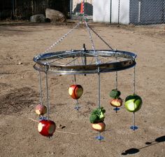 an apple and broccoli wind chime in the middle of a dirt field