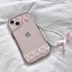 an iphone case sitting on top of a bed next to a pink bow and ribbon