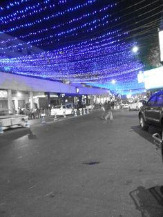 cars are parked in front of a building with blue lights hanging from it's ceiling