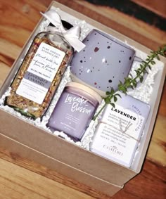 an open box containing lavender essentials on a wooden table with greenery in it