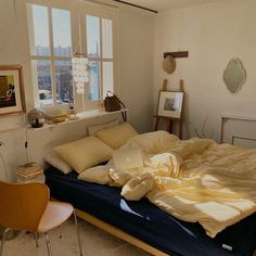 an unmade bed with yellow sheets and pillows in a bedroom next to a window