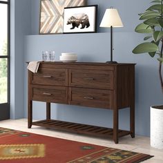 a living room with blue walls and a brown wooden buffet table next to a potted plant