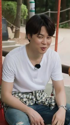 a young man sitting on top of a red swing