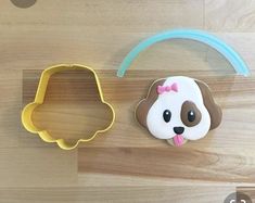 two cookie cutters shaped like dogs on a wooden surface with one dog wearing a bow