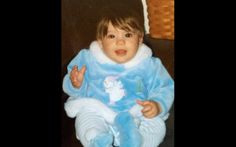 a baby sitting in a chair wearing a blue outfit