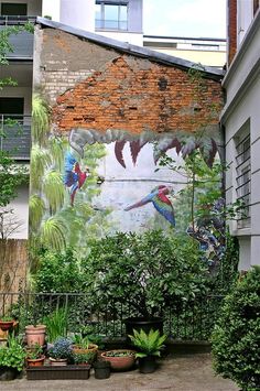 a mural painted on the side of a building with plants and trees in front of it