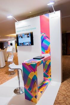 a colorful display in the middle of a room with white tables and chairs around it