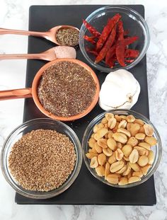 four bowls with different types of food in them sitting on a counter top next to spoons