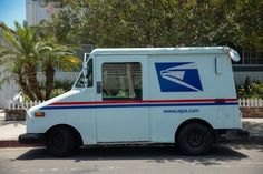 an postal truck is parked on the side of the road with palm trees in the background