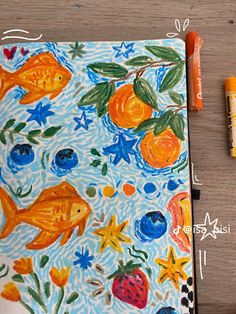 an art journal with oranges, blueberries and strawberries on it next to crayons