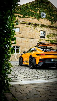 an orange sports car parked in front of a building