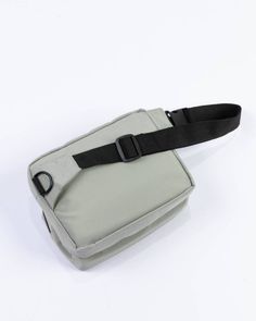 a gray and black belted bag sitting on top of a white table