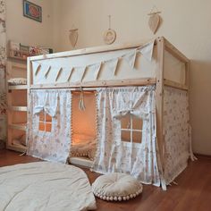 a white bed with curtains and pillows on the floor next to a dog sleeping in it