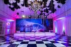 a large room with balloons and chandeliers hanging from the ceiling, decorated in black and white checkered flooring