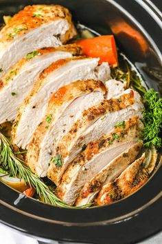 sliced turkey breast in a pan with carrots, parsley and herbs on the side