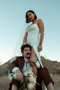 a man sitting on top of a woman's back in the middle of a desert