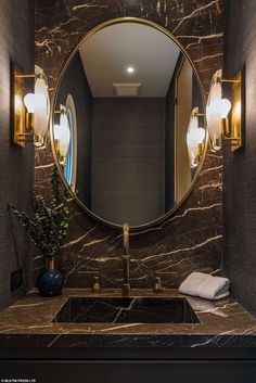 a bathroom sink with a round mirror above it and lights on the wall behind it