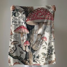 a woman holding up a piece of fabric with mushrooms on it