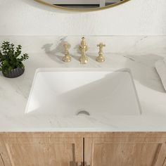 a bathroom sink sitting under a mirror next to a wooden cabinet and counter top with gold faucets