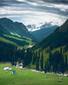 there is a green field in the middle of mountains