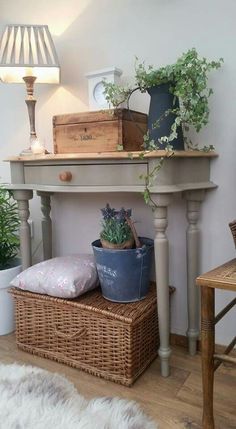 a table with some plants on top of it next to a basket and lamp in the corner