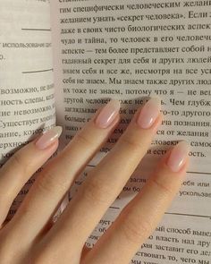 a woman's hand resting on an open book with french manicures and nail polish