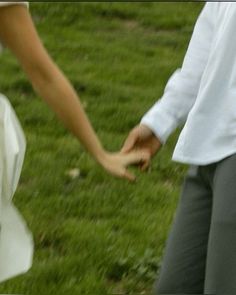 a bride and groom holding hands in the grass