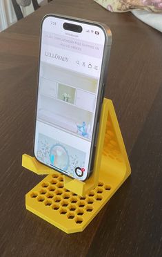 a cell phone sitting on top of a yellow device holder with holes in it's sides