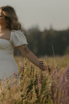 a woman in a white dress walking through tall grass