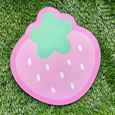 a pink frisbee with a green flower on it sitting in the middle of some grass