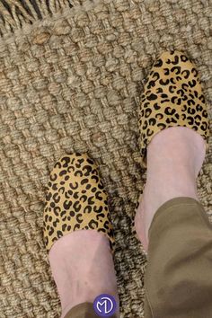 a person wearing leopard print shoes standing on a rug