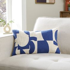 a blue and white pillow sitting on top of a couch in front of a window