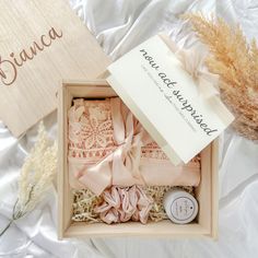 an open box with some items in it on a bed next to dried flowers and a sign