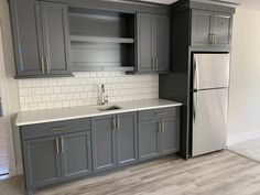 an empty kitchen with gray cabinets and white tile backsplashes on the walls