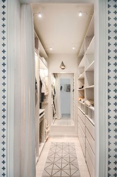 a walk - in closet with white walls and flooring is seen from the doorway