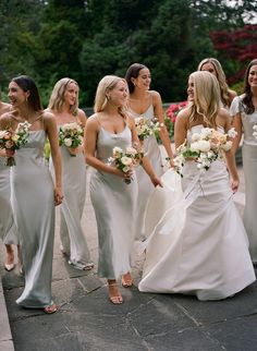 a group of bridesmaids are walking down the street in their wedding gowns