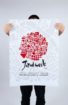 a man holding up a poster with the word tokyo written in japanese and surrounded by small red squares