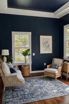 a living room with blue walls and wooden floors, two chairs and a rug on the floor