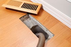 a drain in the floor with a vent on it's side next to a wood floor