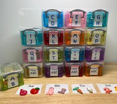 there are many small plastic containers on the table with letters and numbers in them, along with matching cards