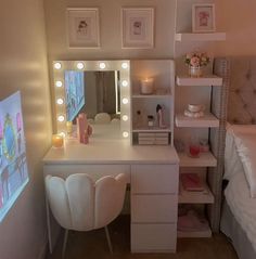 a white vanity with lights on it and a bed in the corner next to it